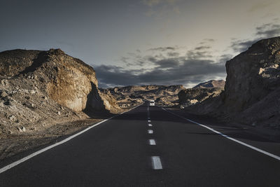 Empty road amidst mountains against sky