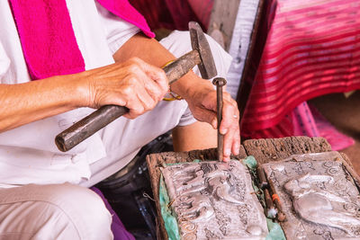 Midsection of male worker carving metal in workshop