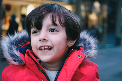 Portrait of cute 4 years old boy with brown hair and red jacket outdoors
