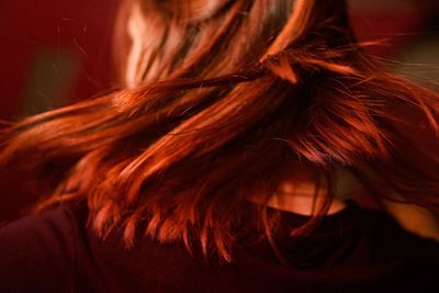 Rear view of redhead woman tossing hair