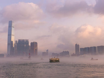 Nautical vessel on sea by buildings against sky in city