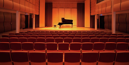 Image of a piano on stage inside an empty concert hall