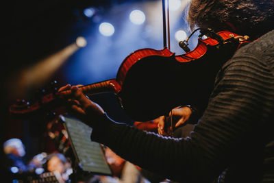 Midsection of man playing violin at music concert