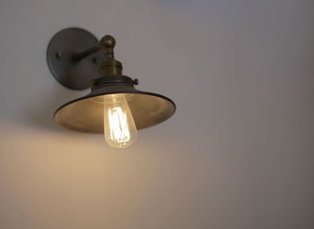 Close-up of illuminated light bulb on white wall