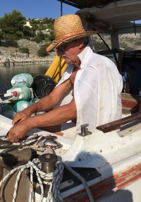 Fisherman cutting fish in boat on sunny day