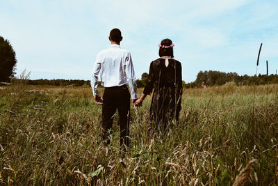 Rear view of men walking on field