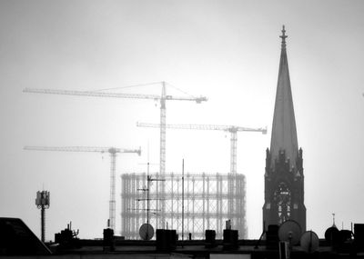 Low angle view of crane and buildings against sky