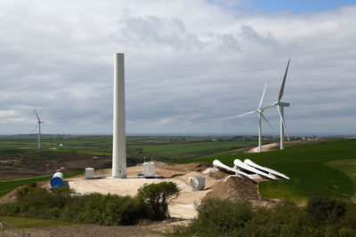 Wind turbines on field against sky