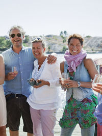 Five people standing with drinks on jetty