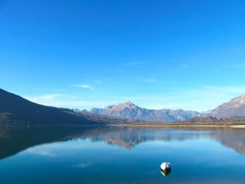 Scenic view of lake and mountains against blue sky