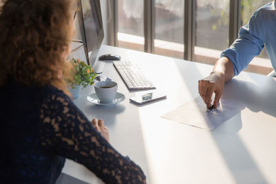 Midsection of woman holding coffee cup on table