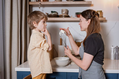 Family fun in the kitchen. mother and son baking carrot cake together. scandinavian kitchen interior