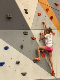 A girl is climbing on a wall making sport