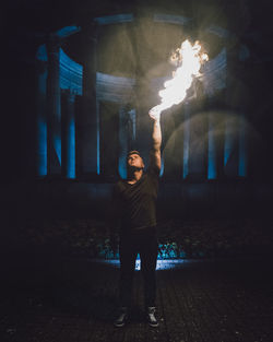 Man with hand burning while standing against historic building at night