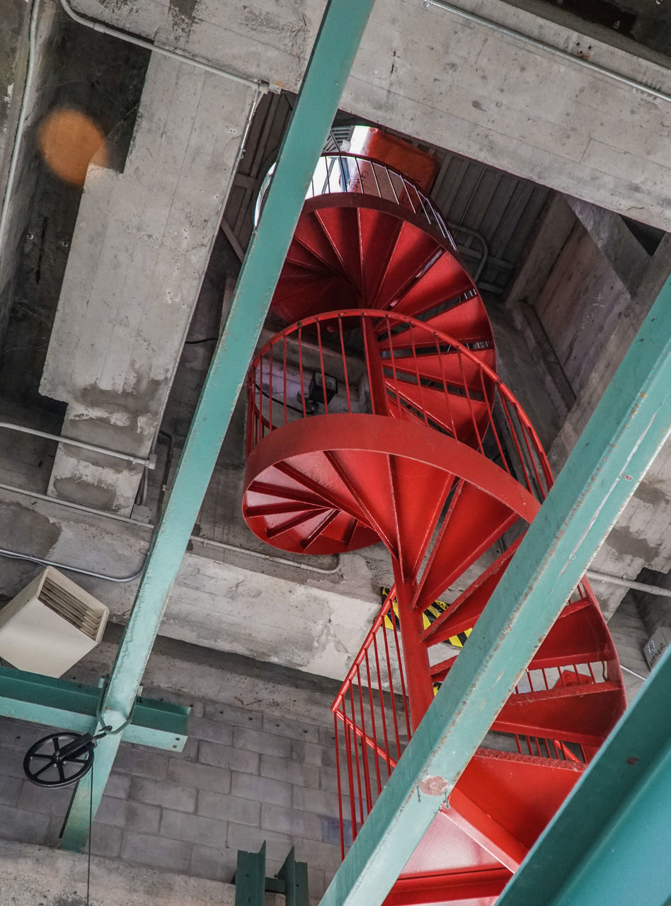 LOW ANGLE VIEW OF RED METALLIC STRUCTURE BY ABANDONED BUILDING