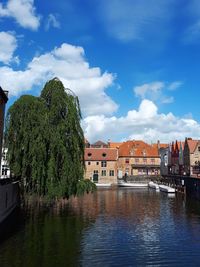 Buildings by river against sky in city