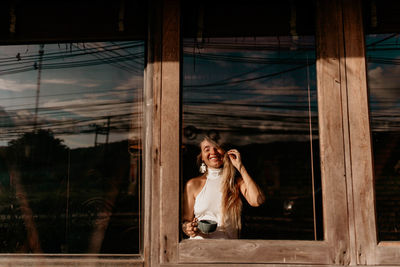 Portrait of young woman looking through window