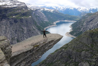 Man standing on cliff against river