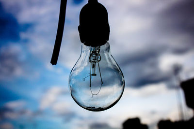 Low angle view of light bulb hanging against sky