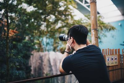 Rear view of man photographing standing by railing