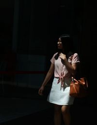 Young woman standing against wall