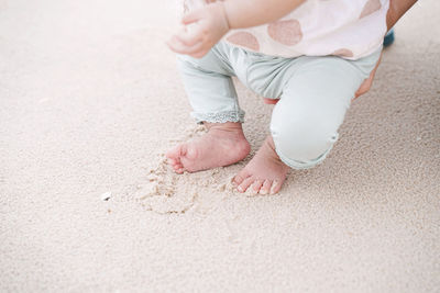 Low section of baby girl on sand at beach