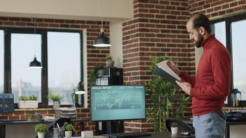 Side view of man using digital tablet while standing in office