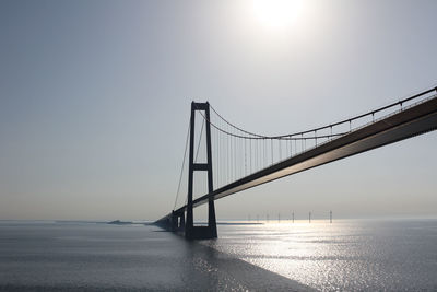 Low angle view of bridge over sea against clear sky on sunny day