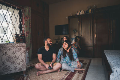 Parents with daughters on carpet in living room at home