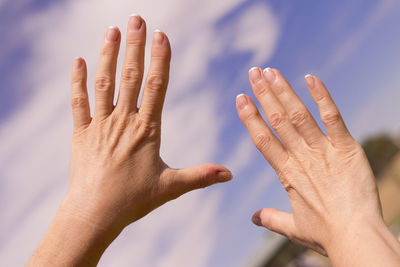 Cropped hands of woman against sky