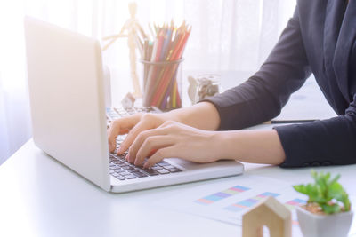 Midsection of woman using laptop on table