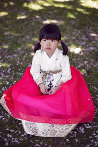 Korean girl child in a national costume walks in a garden with cherry blossoms in spring