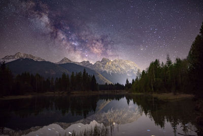 Scenic view of lake and mountains against star field in sky