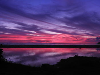 Scenic view of lake against dramatic sky during sunset