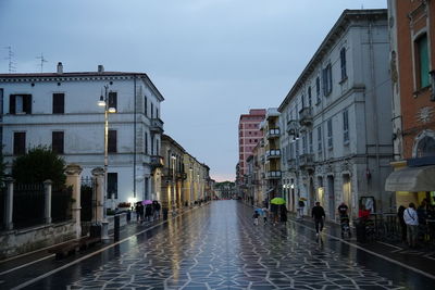 People on street amidst buildings in city