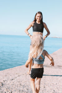 Woman standing with daughter at beach