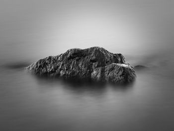 Rock formation in sea against sky