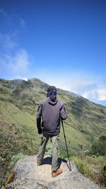 Rear view of man standing on mountain against sky