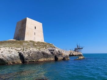 Castle by sea against clear blue sky