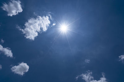 Low angle view of sunlight streaming through clouds