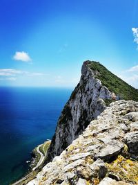 Scenic view of sea by cliff against blue sky