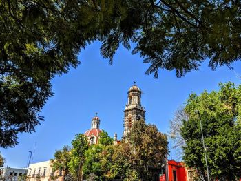 Low angle view of trees and building against sky