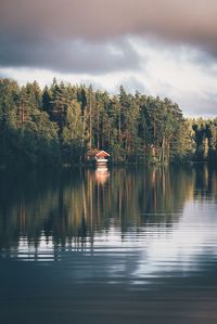 Mid distance view of cottage in lake against cloudy sky