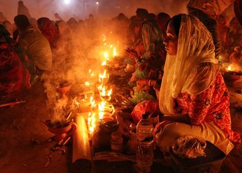 A women is praying at rakher upobash in a smokey environment at baradi lokhnath brahmachari ashram