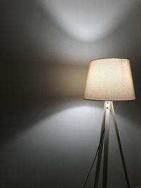 Illuminated lamp against wall at home