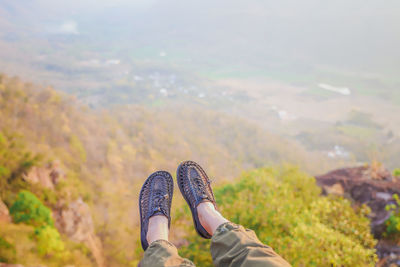 Low section of woman wearing shoes against landscape