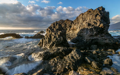 Rock formation on beach against sky