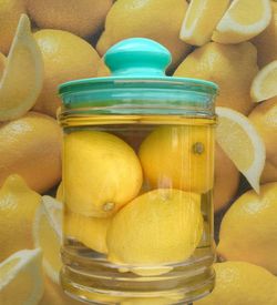 Close-up of lemons in container filled with water against poster