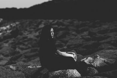 Woman sitting on rock at beach