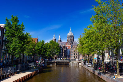 Canal amidst buildings against blue sky